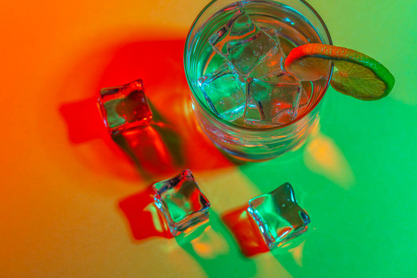 стакан воды с кубиками льда и ломтиком лимона - Фото, изображение