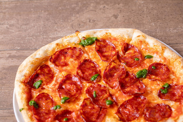 details van lekkere vers gebakken pesto pittige salami pizza - Foto, afbeelding