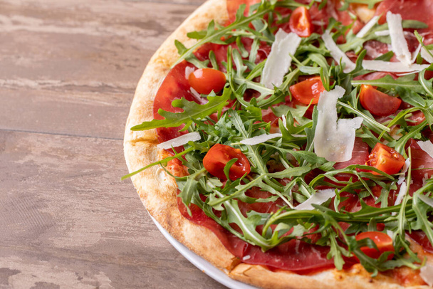 close up of delicious italian fresh pizza with ham, arugula, tomato and parmesan - Foto, Imagen