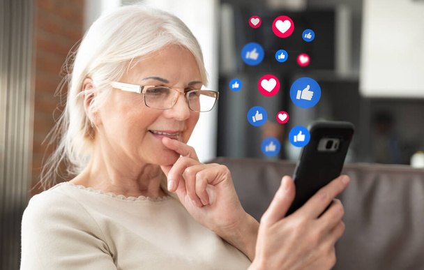 Senior woman using social media. Icons flying from the phone - Фото, изображение
