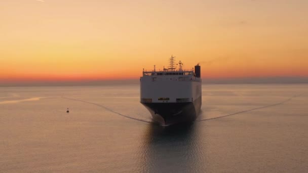 AERIAL: Duży statek towarowy przewozi ciężki ładunek o wspaniałym złotym zachodzie słońca - Materiał filmowy, wideo