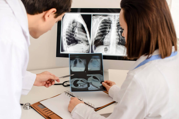 Visão de fundo de jovens médicos radiologistas analisa raio-x e tomografia computadorizada e faz uma descrição médica no caderno - Foto, Imagem