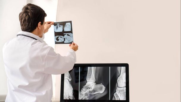 Widok młodego radiologa trzymającego i analizującego zdjęcia rentgenowskie i tomografię komputerową w pokoju rentgenowskim ze szpitala. Kopiuj miejsce dla Ciebie tekst - Zdjęcie, obraz
