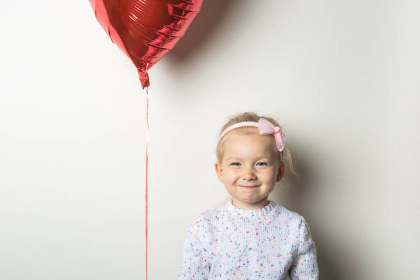 Little girl and heart air balloon on a light background. Concept for Valentine's Day, birthday. Banner. - Φωτογραφία, εικόνα