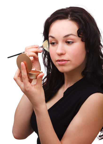 Girl is applying rouge while looking at mirror - Фото, зображення