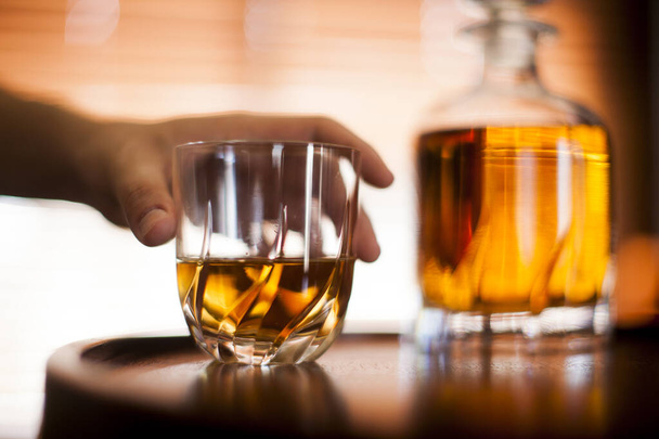 İnsan eli, viski bardağı karanlık bir bar ortamında kapanıyor. Bardağa odaklan. Boşluğu kopyala. Yüksek kalite fotoğraf - Fotoğraf, Görsel