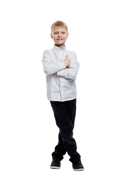 Smiling boy stands with his arms crossed. A guy in a white shirt and dark trousers. Success and confidence. Full height. Isolated on white background. Vertical. - Fotó, kép