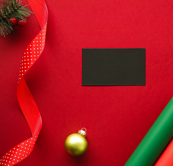 Diseño de identidad de marca de vacaciones y concepto flatlay de Navidad. Tarjeta de visita en blanco negro y adorno de Navidad y decoración sobre fondo de papel rojo como maqueta plana - Foto, imagen