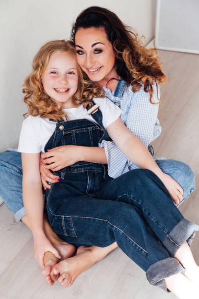 мать и дочь в джинсах обнимаются и улыбаются - Фото, изображение