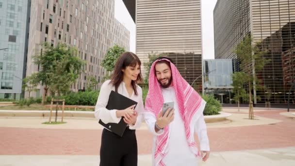 Deux collègues différents discutent avec l'équipe en ligne via smartphone lors d'un voyage d'affaires à Dubaï - Séquence, vidéo