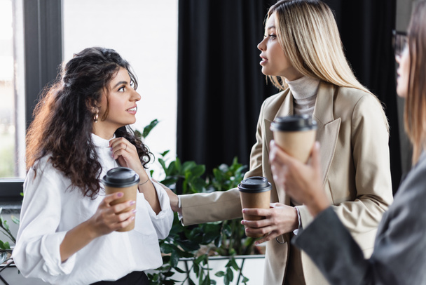 junge Geschäftsfrauen halten Pappbecher in die Höhe, während sie in der Kaffeepause in Ofice reden - Foto, Bild