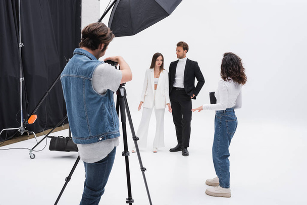 director de arte hablando con modelos cerca del fotógrafo durante la sesión de fotos - Foto, Imagen