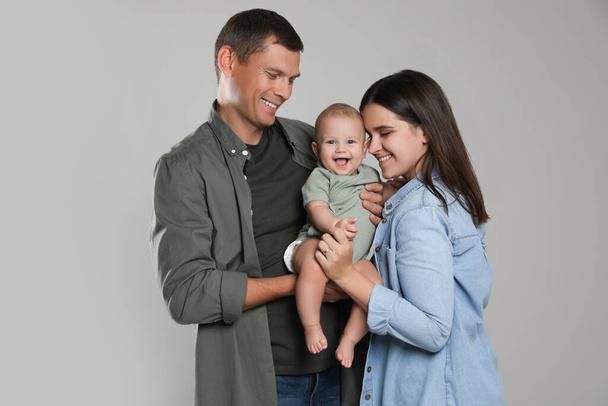 Familia feliz. Pareja con su lindo bebé sobre fondo gris - Foto, Imagen
