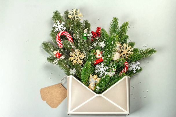 Christmas festive composition with fir tree branches, New Year toys, snowflakes, and traditional decoration. Envelope, gray background, creative flat lay, top view - Valokuva, kuva