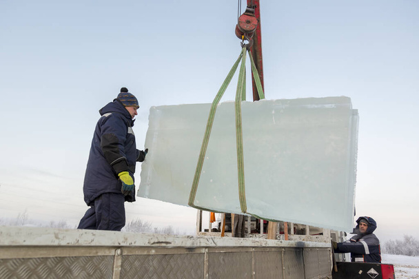 Dos trabajadores de ensamblaje descargan placas de hielo del cuerpo de un automóvil - Foto, imagen