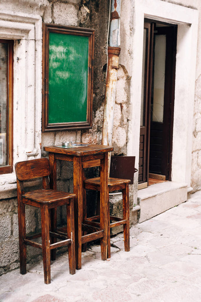 Fa magas asztal és két szék közel a falhoz egy kis bár az utcán - Fotó, kép