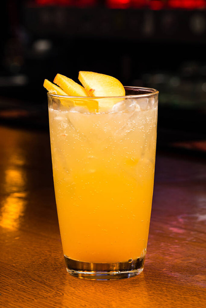 peach iced tea or lemonade with peach, peach cocktail at the bar on wooden background, juice with fresh peach slices with ice cubes, - Foto, Imagen