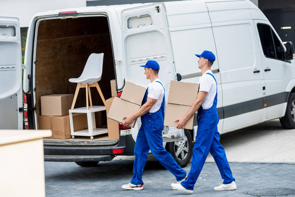 Két költöztető cég dolgozói dobozokat és bútorokat pakolnak egy minibuszba.. - Fotó, kép