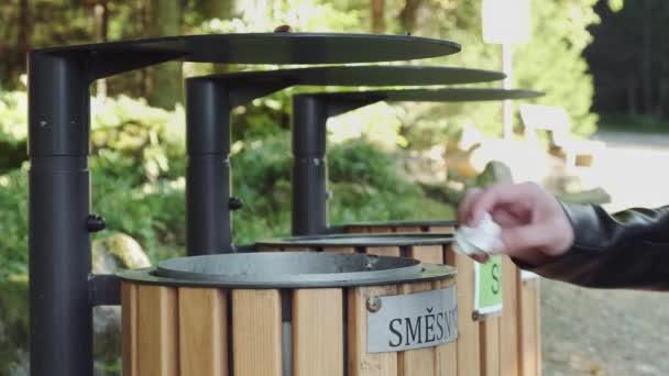 Turisti heittää paperia roskakoriin kansallispuistossa - Materiaali, video