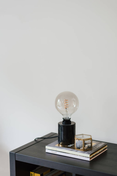 A vertical shot of electric lamp with a light bulb in vintage style put on books - Φωτογραφία, εικόνα