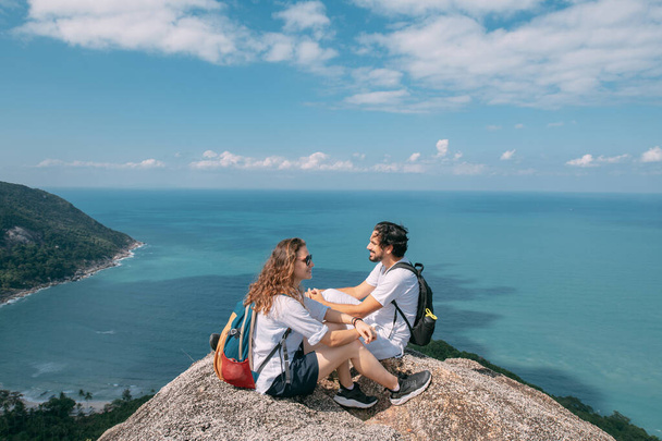 Una pareja está parada sobre una roca en un mirador con una vista épica del océano. Un destino turístico popular. Amantes de vacaciones en los trópicos. Luna de miel en los trópicos. - Foto, Imagen