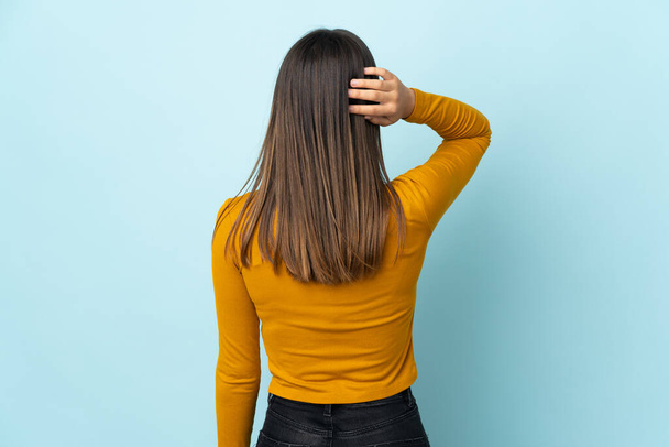 Teenager Mädchen isoliert auf blauem Hintergrund in Rückenlage und Denken - Foto, Bild
