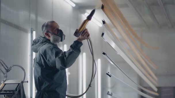 Egy ember a lélegeztetőgépben fémet fest poros módszerrel. Festőműhely. A festő dolgozik egy szórópisztoly festék alkalmazzák - Felvétel, videó
