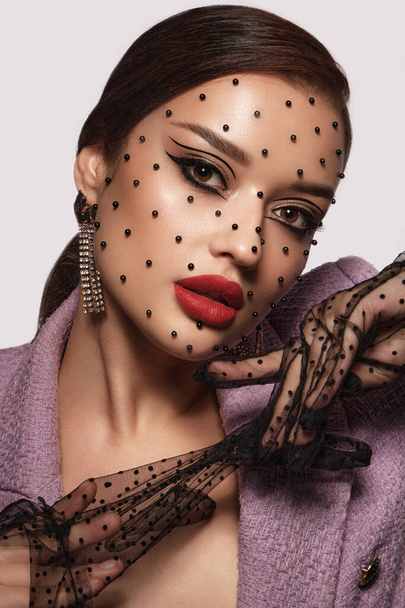 Portrait of a beautiful woman with creative makeup, black beads on her face in a fashion style. Beauty face. - 写真・画像