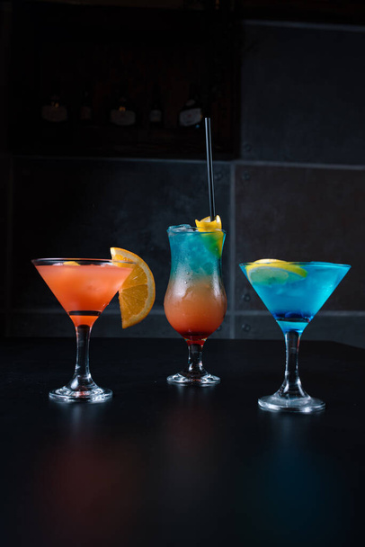 The delicious and refreshing cocktails in blue and orange color gradient at the bar table - Фото, зображення