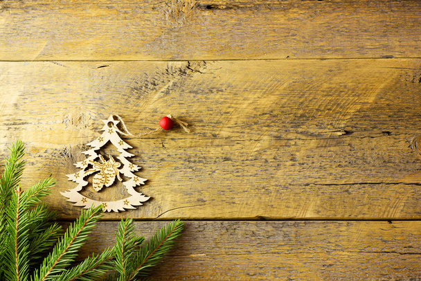 Старинный рождественский фон - старая деревянная доска с сосновой ветвью, шишками и деревянной игрушкой. - Фото, изображение
