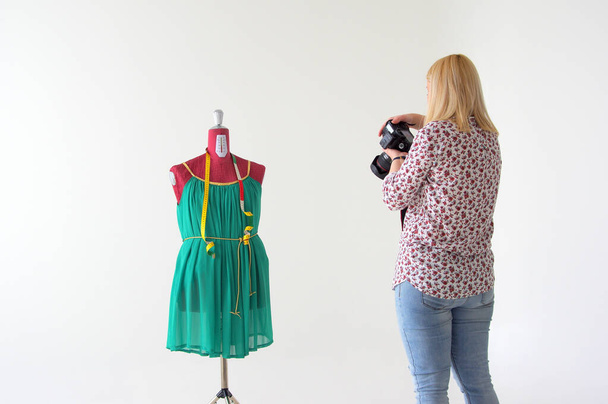 A photographer female taking pictures of the tailor's mannequin with a green dress a - Valokuva, kuva