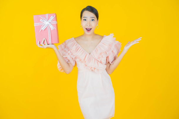 Портрет красивая молодая азиатская женщина улыбка с красной коробке подарка на цветном фоне - Фото, изображение