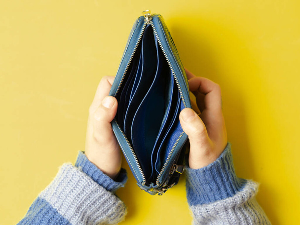 girl opens empty wallet on yellow background, concept of poverty and no money - Photo, Image