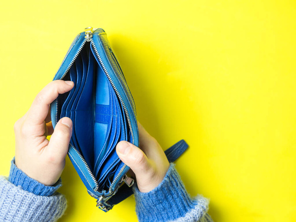 Mädchen öffnet leere Brieftasche auf gelbem Hintergrund, Konzept der Armut und kein Geld - Foto, Bild
