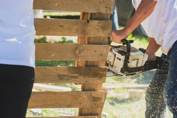 Man with chainsaw working with pallets - Foto, afbeelding