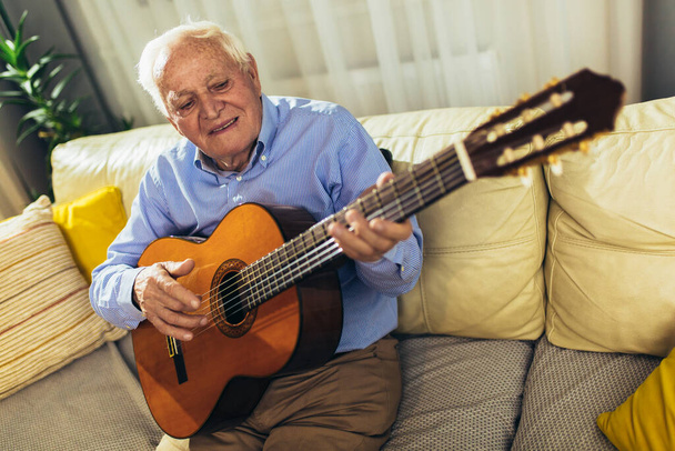 Senior man playing guitar at home - Foto, Imagem