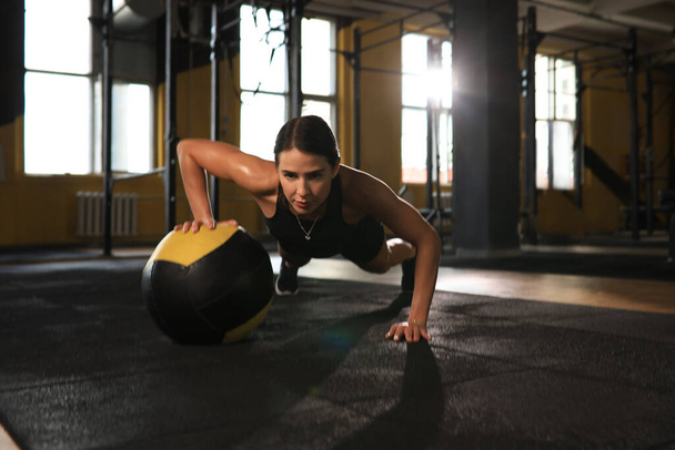 Fit and muscular woman exercising with medicine ball at gym - Foto, Bild