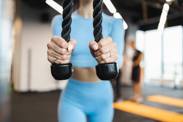 Woman doing pushdowns with rope for triceps at the gym closeup - Photo, Image