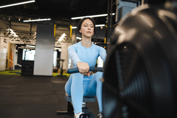 Sporty woman on rowing machine in gy - Photo, Image
