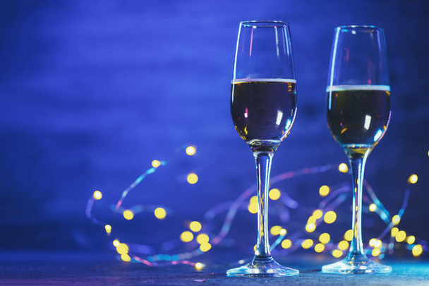 Due bicchieri di champagne, sfondo colore pantone. Brindisi di Natale, ghirlande di bokeh e spazio per copiare - Foto, immagini