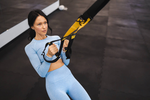 Athletic woman doing exercise with trx system - Фото, зображення