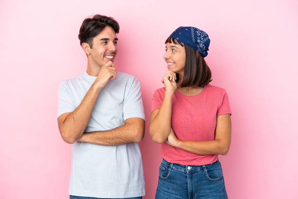 Young couple isolated on pink background looking looking at each other - Photo, Image
