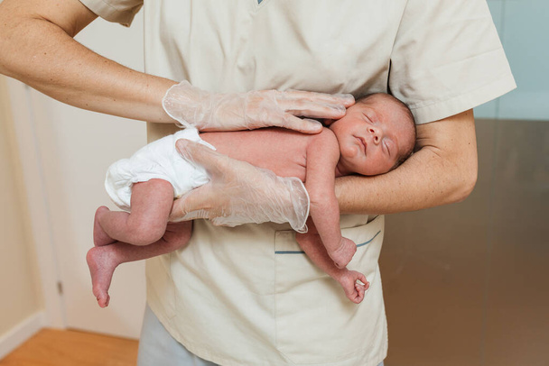 Στενή άποψη ενός γιατρού που εξετάζει ένα νεογέννητο μωρό. - Φωτογραφία, εικόνα