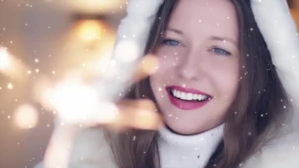 Vacaciones de invierno y concepto de celebración de Navidad. Hermosa mujer sonriente en abrigo de piel esponjosa blanca sosteniendo bengalas ardientes, nevando nieve y copos de nieve - Metraje, vídeo