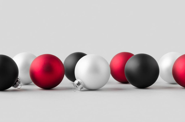 Multiple white, red and black matte Christmas balls mockup on a seamless grey background. - Foto, Imagem