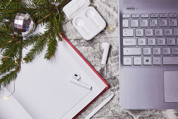 Notepad mock up and wireless earphones and laptop. Freelance, remote work, taking webinar, calling to family concept. New year's goals and resolutions mock up. Christmas, New Year's present concept - Photo, Image