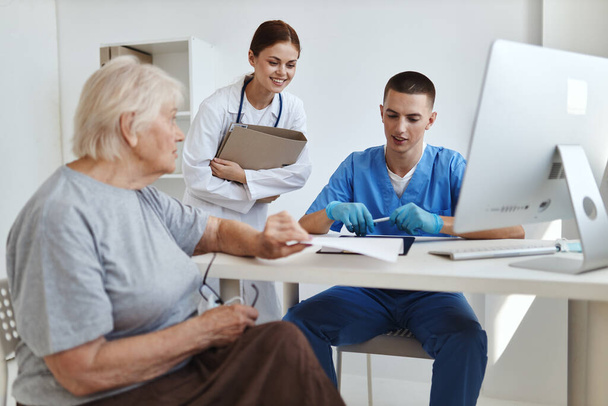 starší žena komunikuje s lékařem a zdravotní sestrou ve zdravotnické nemocnici - Fotografie, Obrázek