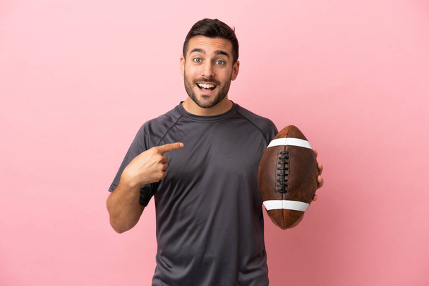 Young caucasian man playing rugby isolated on pink background with surprise facial expression - Photo, Image