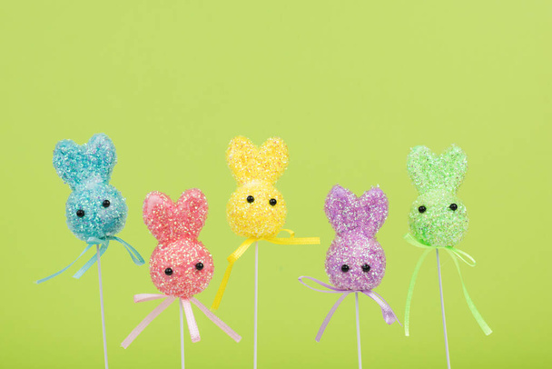 Colorful Easter bunnies on a green background. The concept of Easter holidays. - Photo, Image