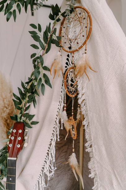 Photozone in the form of a tipi decorated in boho style with greenery - Фото, изображение